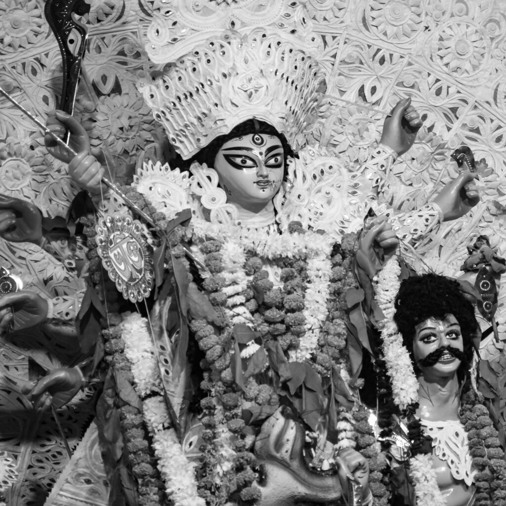 Intricate black and white sculpture of Hindu Goddess Durga adorned with flowers and ornaments.